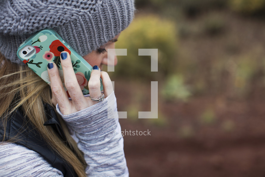 A woman in winter clothes talked on a cell phone with a colorful cover.