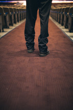 feet of a man standing in the aisle of a church 