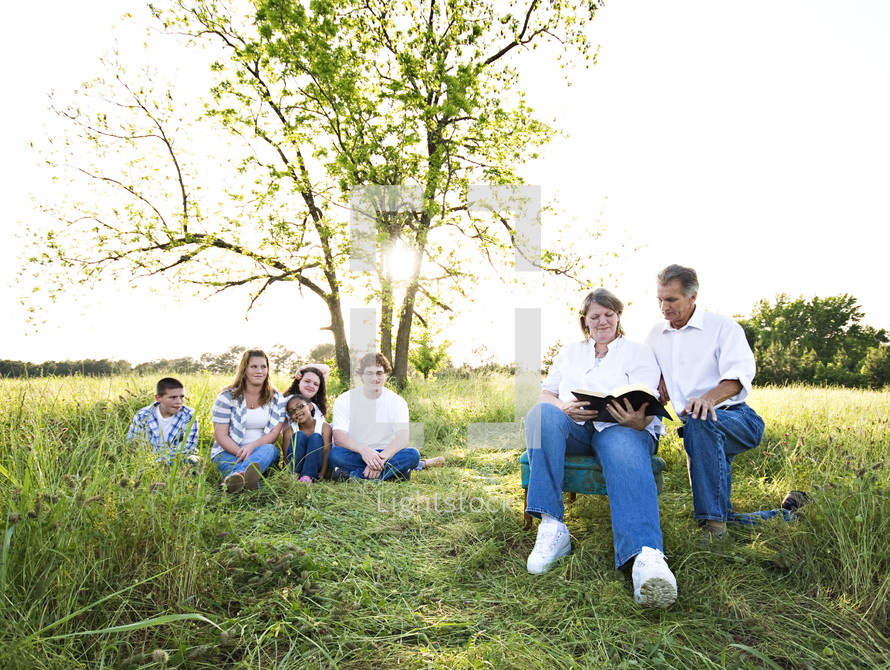 family reading the Bible together outdoors