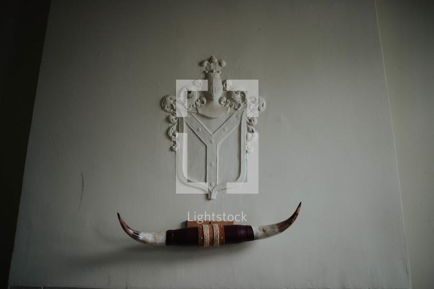 Mounted horns below a crest on a wall.