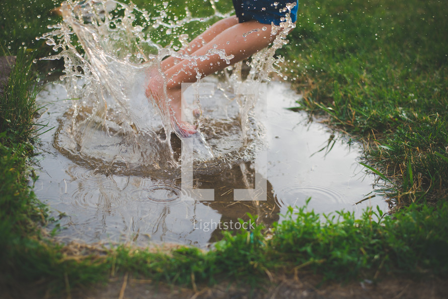 a boy jumping in a puddle 
