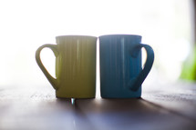 Light surrounding yellow and blue coffee cups.
