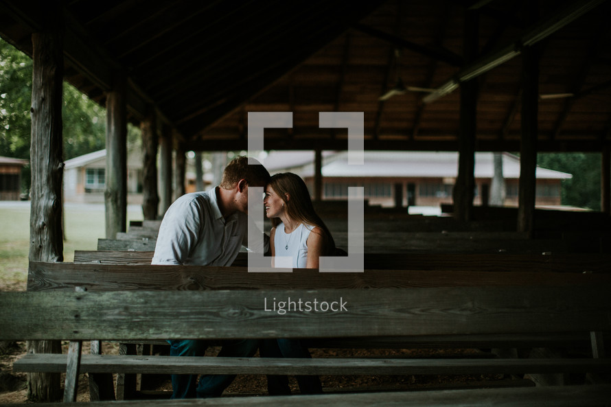 couple sitting in wooden pews outdoors - couple's retreat  