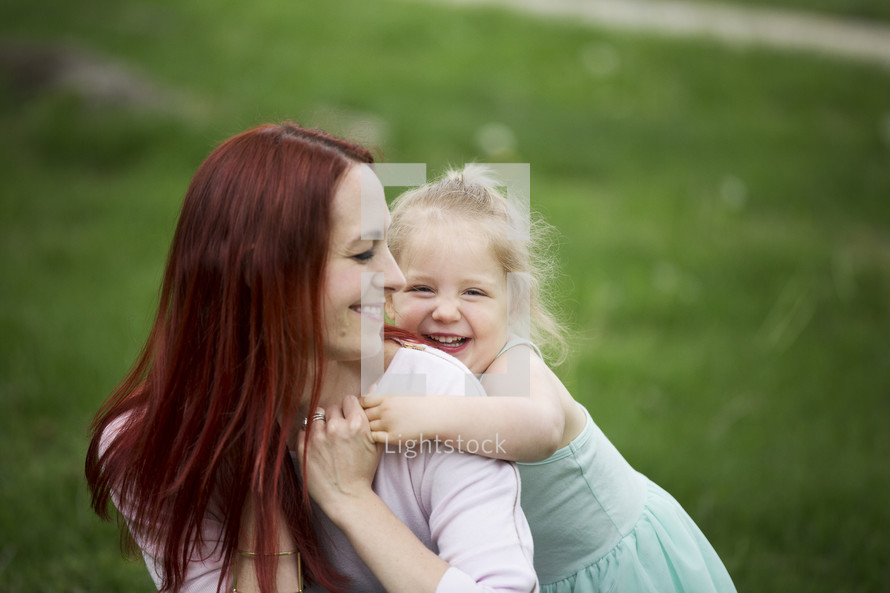 A mother and daughter laughing together outdoors.