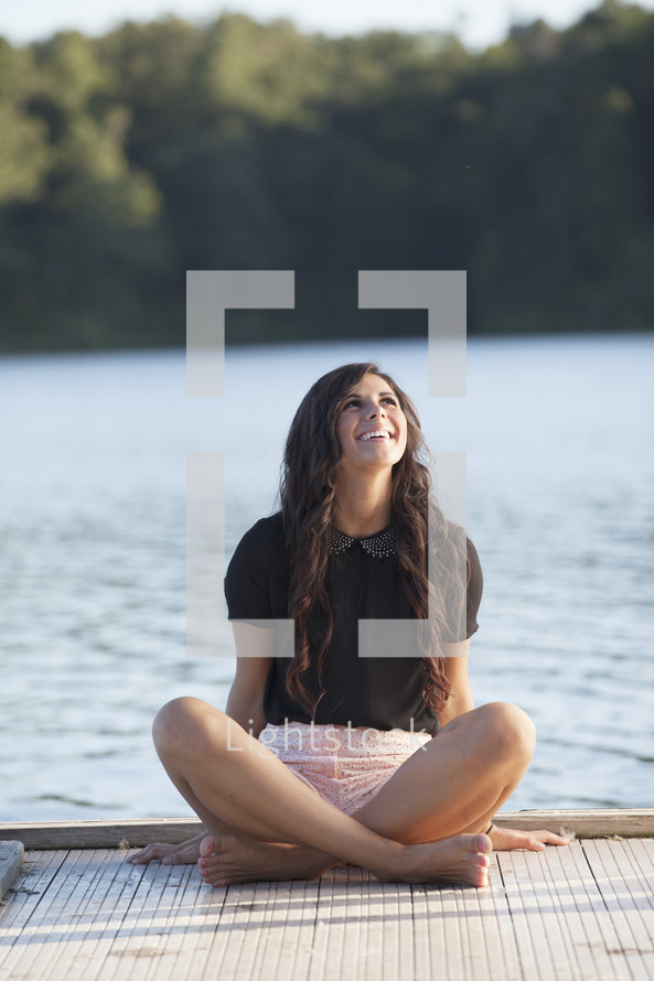woman sitting on a dock looking up smiling 