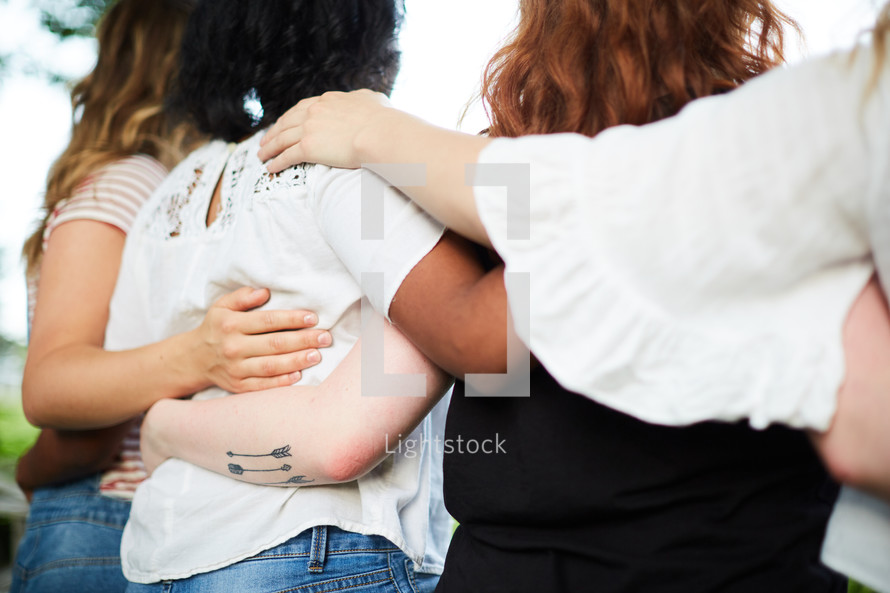 woman standing with arms around each other 