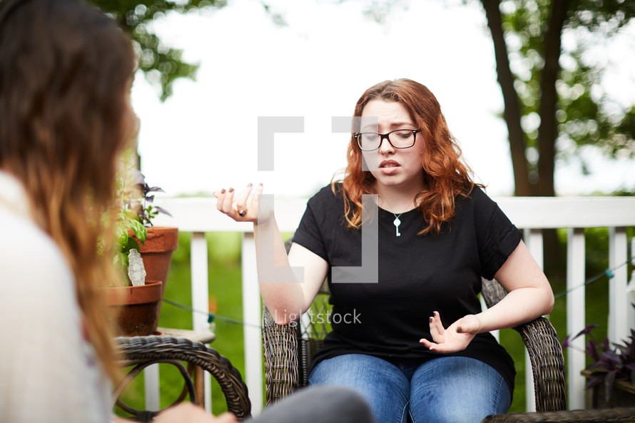 women talking together sitting on a patio outdoors 