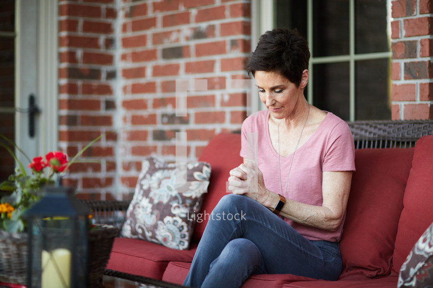 a woman sitting on a porch praying 