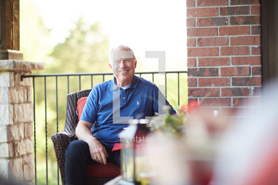a smiling man sitting on a porch 