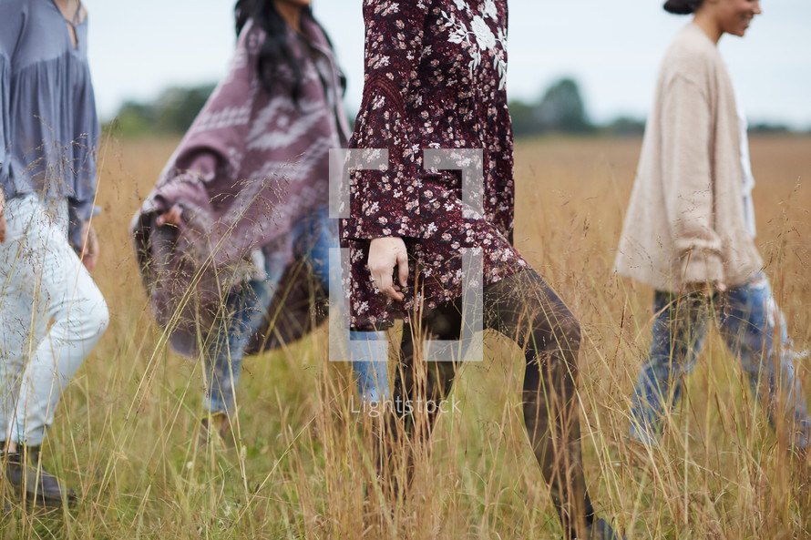 women walking through tall grasses in a field 