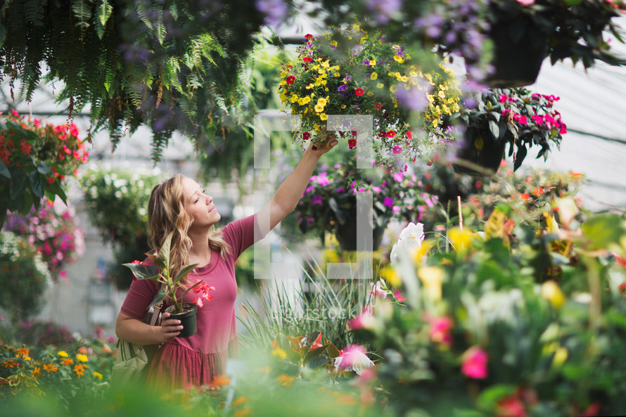 a young woman picking out flowers at a garden center 