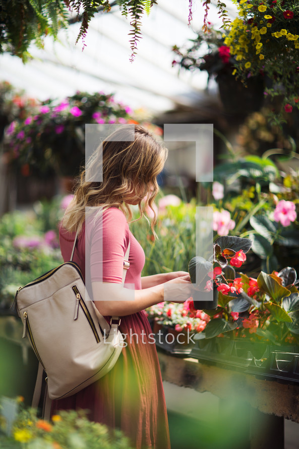 a young woman picking out flowers in a garden center greenhouse 