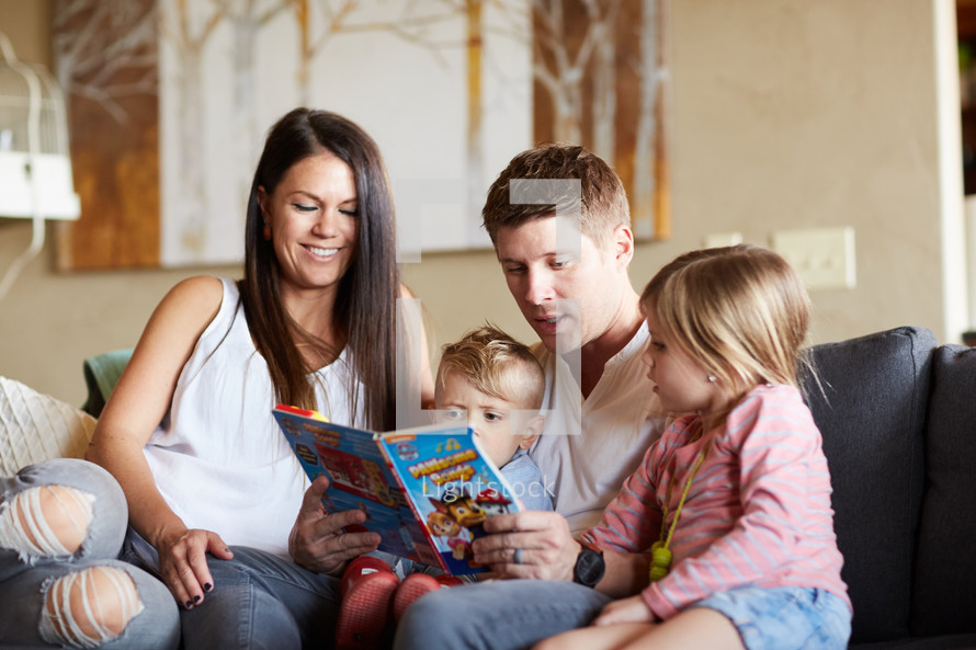 a family reading a children's book on the couch 