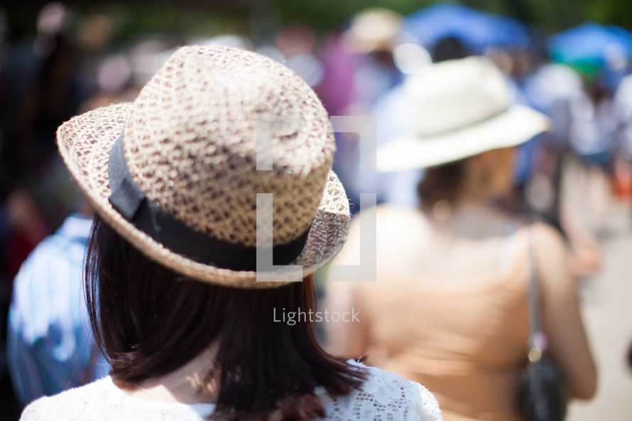 woman in a straw hat walking in a crowd 