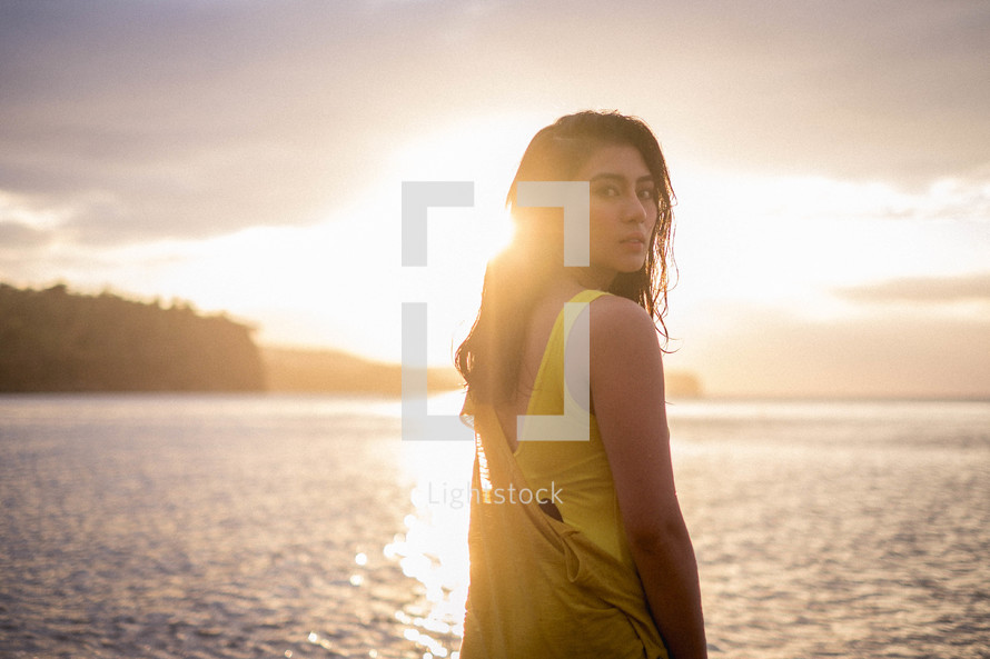 a young woman standing on a beach at sunset 