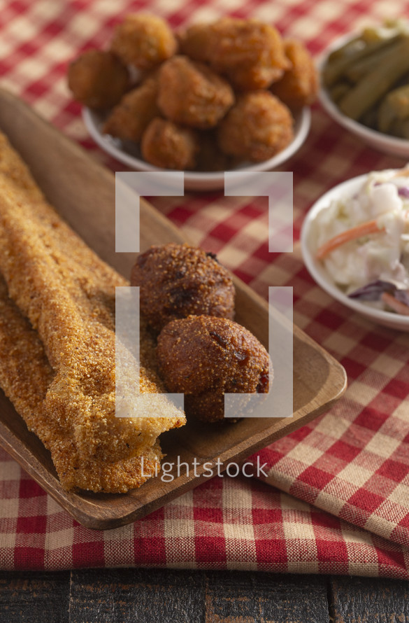 Breaded and Fried Fillets of Fish with Hushpuppies on a Rustic Wooden Table