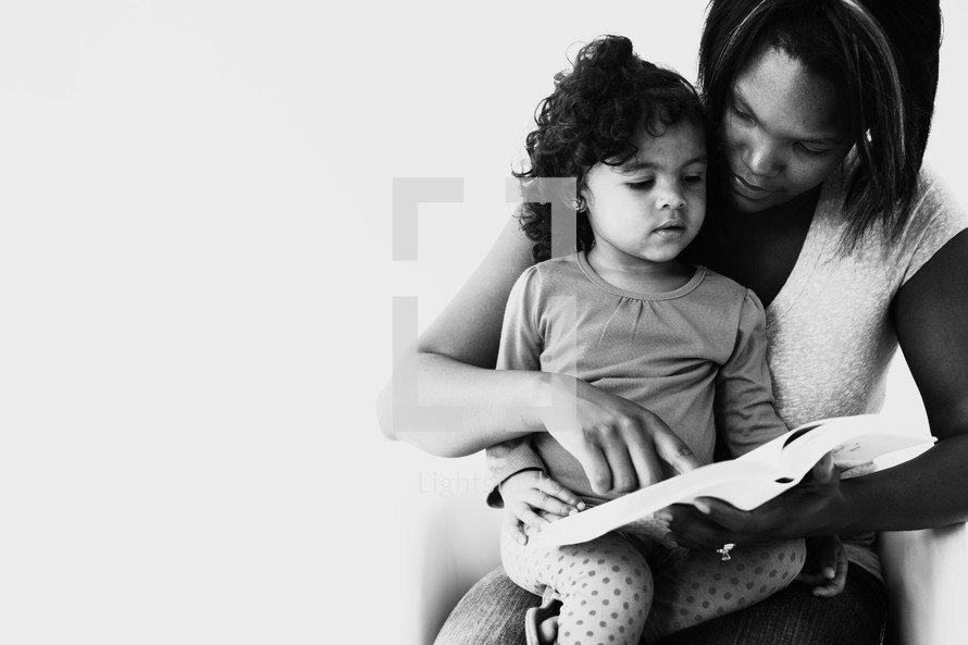 mother and toddler daughter reading a Bible together 