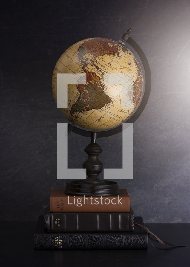 Stack of Bibles and a Globe on a Dark Background