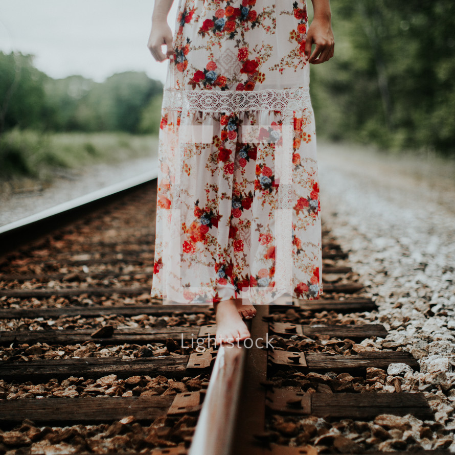 young woman balancing on train tracks