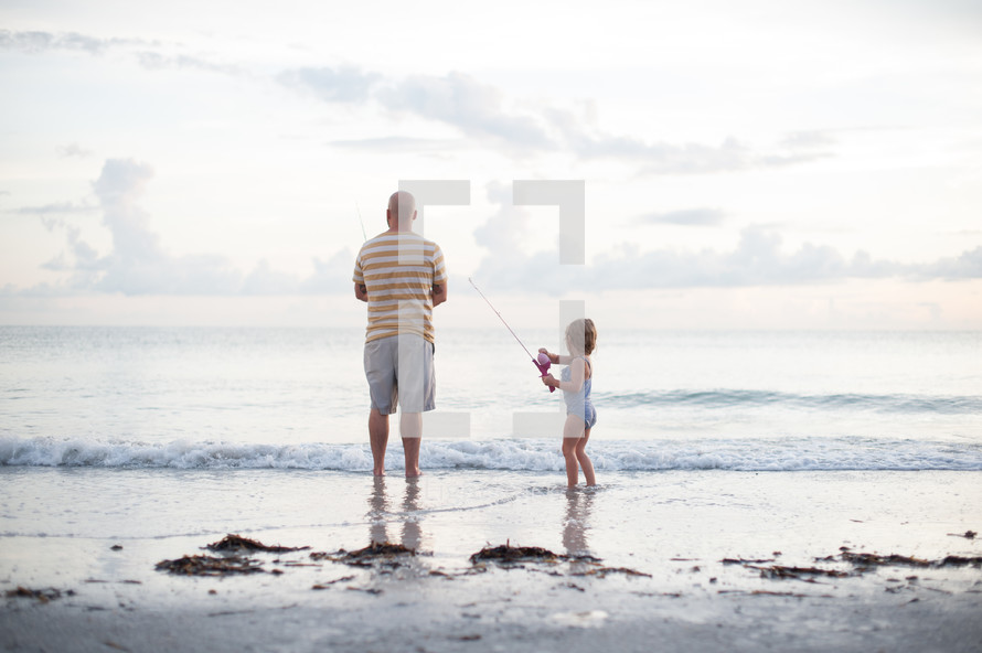 father and daughter fishing on a beach 
