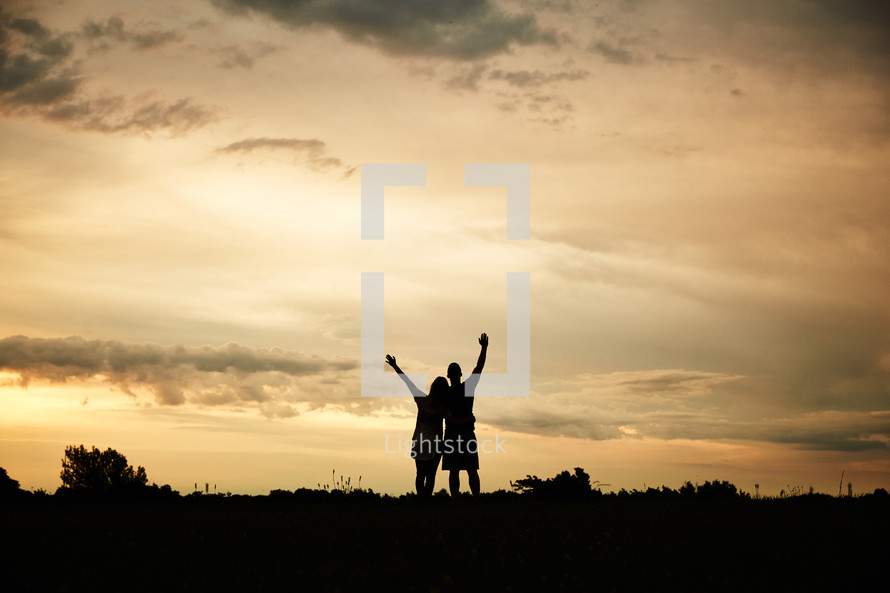 silhouettes of a couple with raised hands 