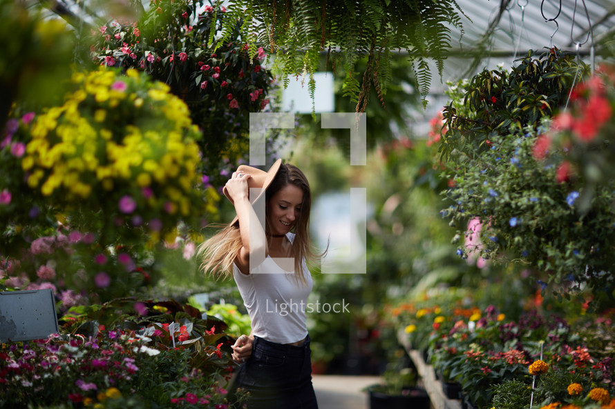 a woman standing in a greenhouse surrounded by plants 
