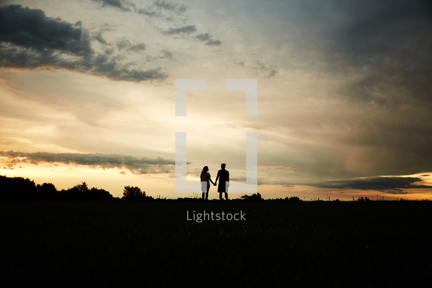 a silhouette of couple holding hands 