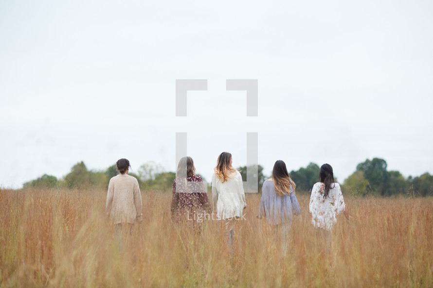 group of women walking through a field 
