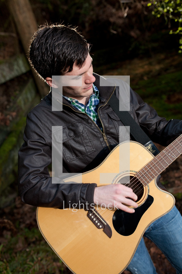 man playing a guitar in a forest