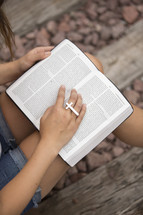 woman reading a Bible and a cross ring