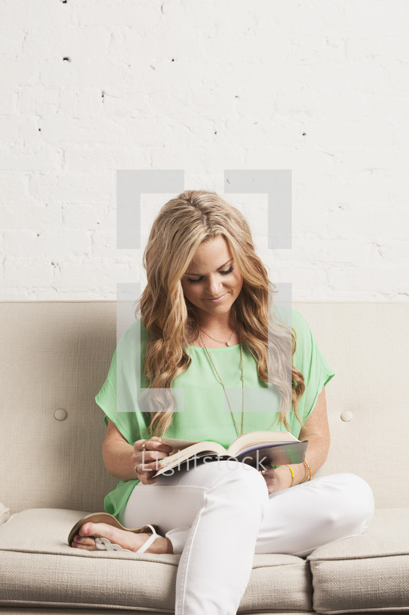 woman reading a Bible sitting on a white couch