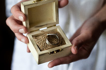 A bride holds a small box containing the bride's and groom's rings.