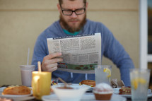 a man reading a newspaper over breakfast 