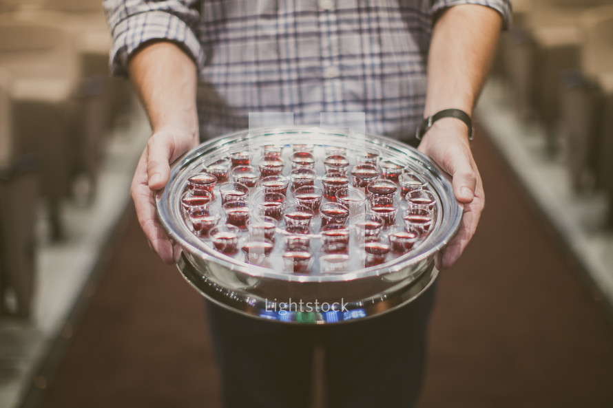 man holding a tray of communion cups