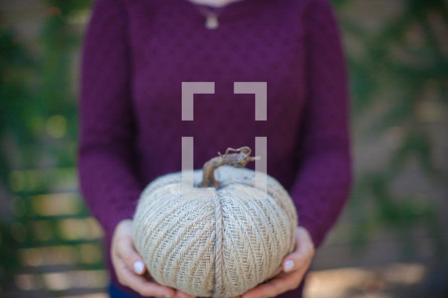 a woman holding a burlap pumpkin 