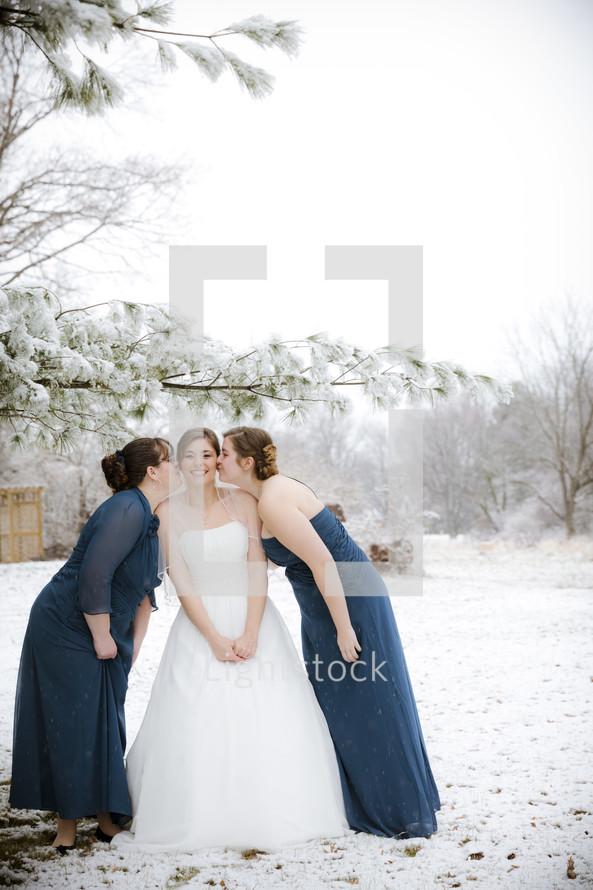 bridesmaids kissing a bride on the cheeks 