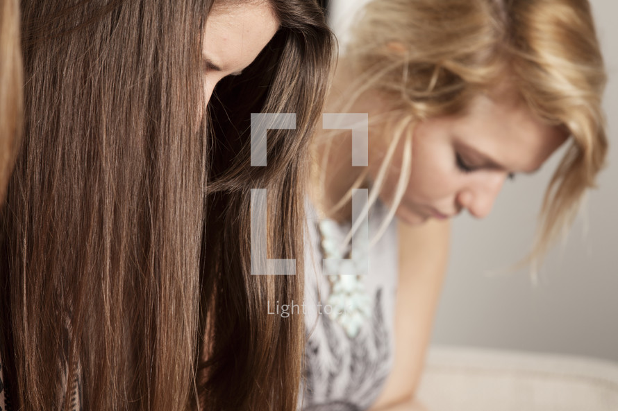 two young women looking down in prayer 