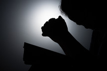 Silhouette of an Asian woman praying