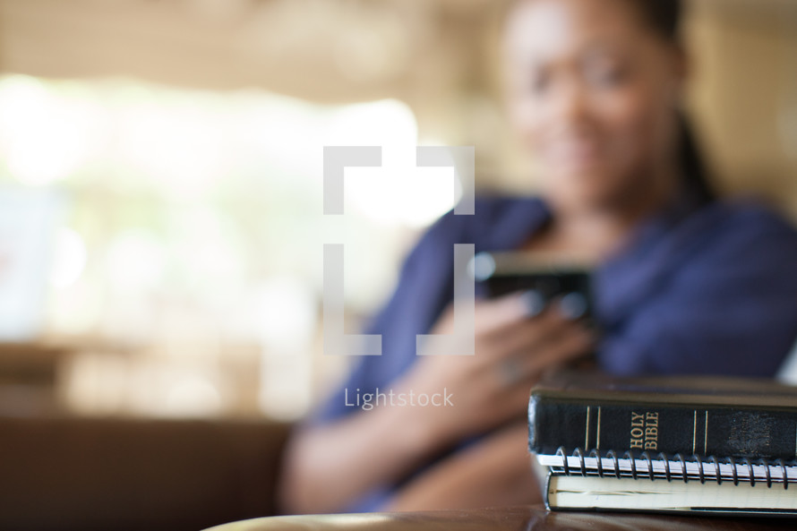 Woman texting near a Bible.