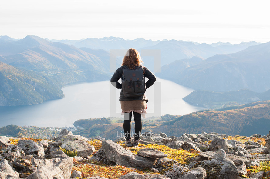 a woman looking out at a lake in a mountain valley 