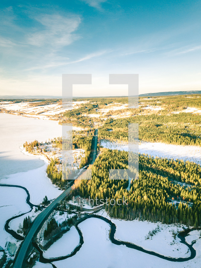 aerial view over a highway and winter forest 