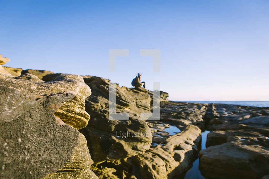 woman sitting on rocks at a beach 