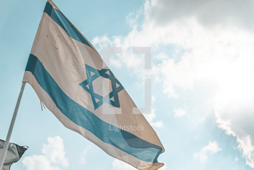 The flag of Israel against blue sky with clouds