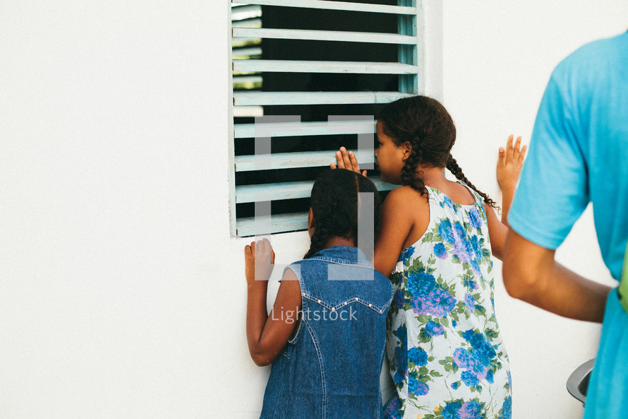girl children peeking in a window 