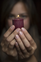 woman holding a burning red candle