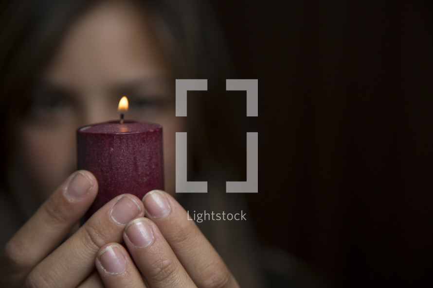 woman holding a red burning candle 