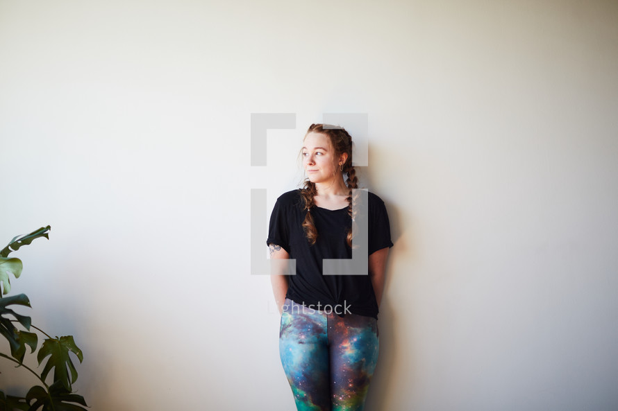 woman in yoga pants leaning against a white wall 