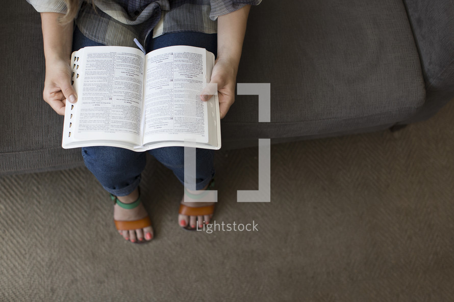 woman sitting on a couch reading a Bible
