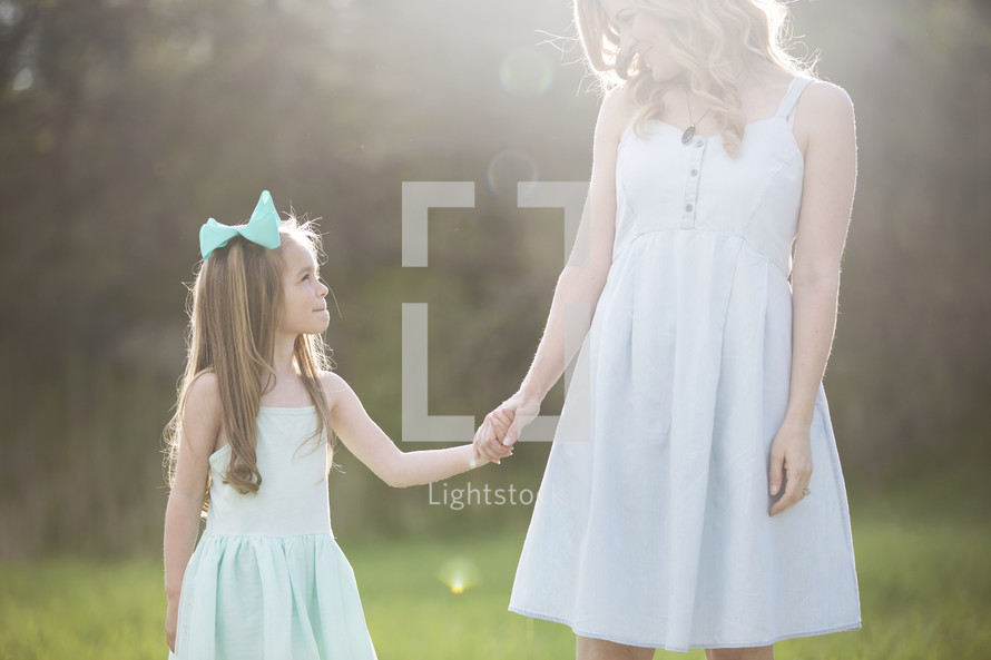 a mother and daughter holding hands outdoors 