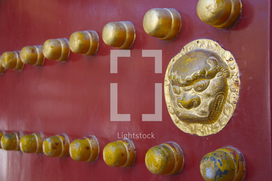 decorative gold ornamental pieces on a red door in China